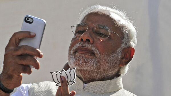 FILE- In this 30 April 2014 file photo, India's main opposition Bharatiya Janata Party's prime ministerial candidate Narendra Modi holds his party's symbol and looks into his phone after casting his vote in Ahmadabad, India. - Sputnik International