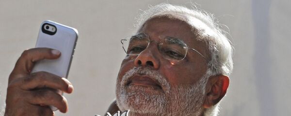 FILE- In this April 30, 2014 file photo, India's main opposition Bharatiya Janata Party's prime ministerial candidate Narendra Modi holds his party's symbol and looks into his phone after casting his vote in Ahmadabad, India - Sputnik International