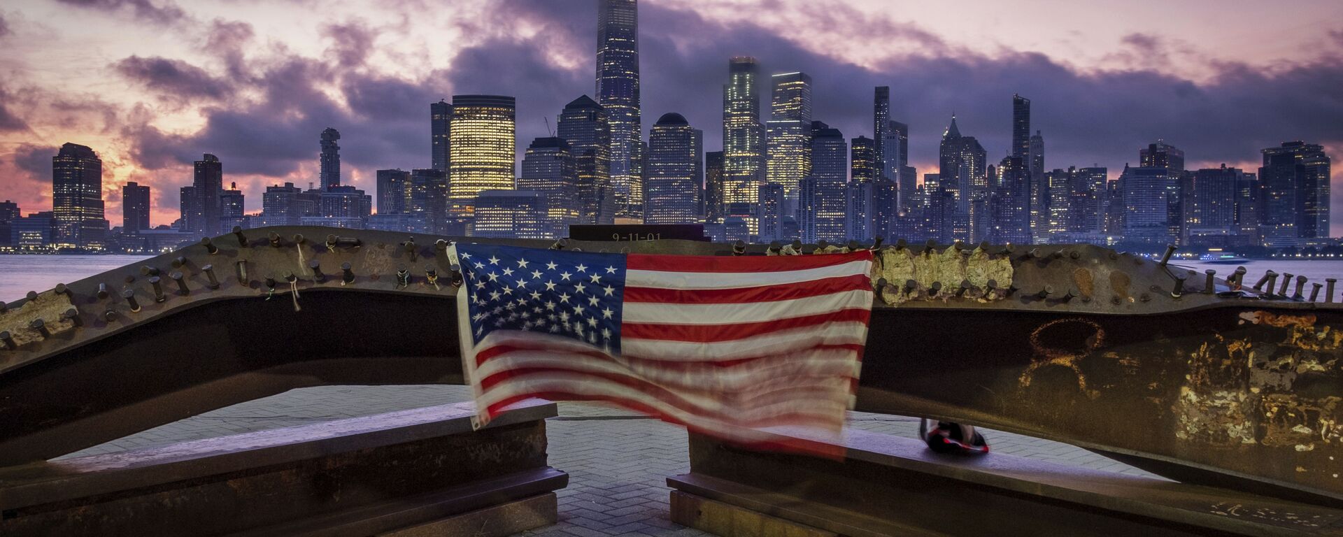A US flag hanging from a steel girder, damaged in the 11 September 2001 attacks on the World Trade Center, blows in the breeze at a memorial in Jersey City, New Jersey on 11 September 2019. - Sputnik International, 1920, 06.09.2021