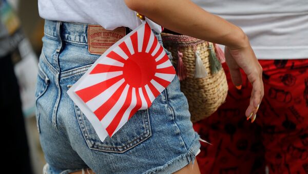 A woman carries an Imperial Japanese flag as she visits the Yasukuni Shrine in Tokyo, Japan August 15, 2019, on the 74th anniversary of Japan's surrender in World War Two.  - Sputnik International