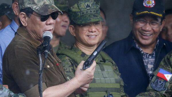 President Rodrigo Duterte holds a pistol as he addresses the troops as he declared the liberation of Marawi city in the southern Philippines after almost five months of a siege by pro-Islamic State group militants Tuesday, Oct. 17, 2017 - Sputnik International