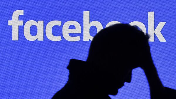 A man passes a facebook screen - Sputnik International