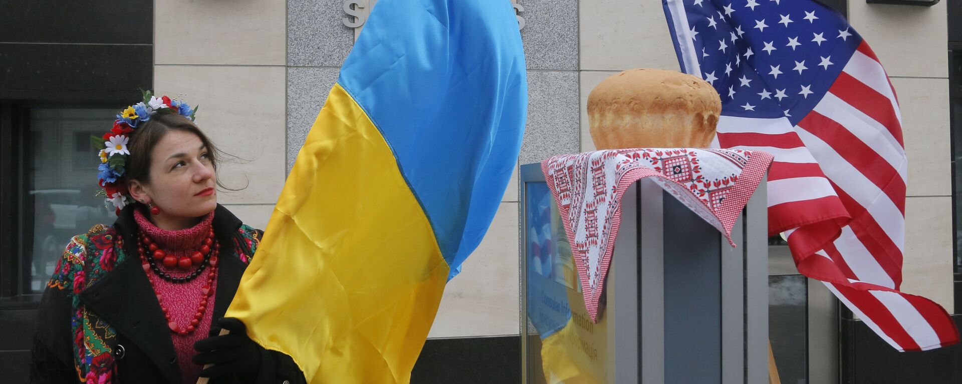 A woman holds a Ukraine flag and looks up at the traditional Ukrainian bread and salt in front of the US embassy in Kiev, Ukraine, Friday, Jan. 20, 2017, in support of Donald Trump hours before he is to be sworn in as president of the United States. - Sputnik International, 1920, 14.02.2022