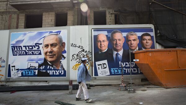 A man walks by election campaign billboards showing Benjamin Netanyahu, left, alongside the Blue and White party leaders - Sputnik International