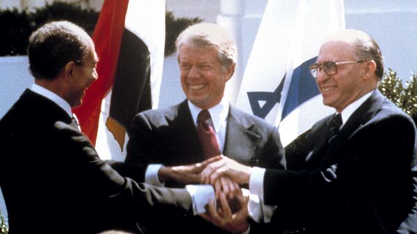In this file photo taken 26 March 1979, Egyptian President Anwar Sadat, left, US President Jimmy Carter, centre, and Israeli Prime Minister Menachem Begin clasp hands on the north lawn of the White House as they complete the signing of a peace treaty between Egypt and Israel. When Israeli Prime Minister Menachem Begin shook hands with Egyptian President Anwar Sadat on the White House lawn, ordinary Israelis saw not only an end to war with their largest neighbour but also the hope of warm relations with the people next door. - Sputnik International