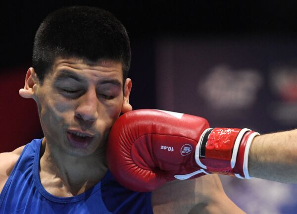 Argentina's Brian Agustin Arregui, in blue, takes a punch from Uzbekistan's Bobo-Usmon Baturov, in red, during their 63-69 kg preliminaries bout at the 20th Men's World Boxing Championship, in Yekaterinburg, Russia. - Sputnik International