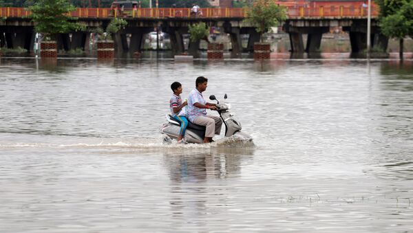 A man and a boy ride a scooter through a flooded road after heavy rains in Prayagraj, India, September 29, 2019 - Sputnik International