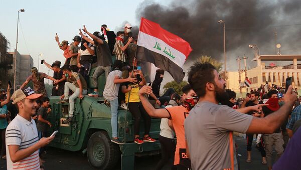 Anti-government protesters take over an armored vehicle before they burn it during a demonstration in Baghdad, Iraq, Thursday, Oct. 3, 2019. Iraqi security forces fired live bullets into the air and used tear gas against a few hundred protesters in central Baghdad on Thursday, hours after a curfew was announced in the Iraqi capital on the heels of two days of deadly violence that gripped the country amid anti-government protests. (AP Photo/Hadi Mizban) - Sputnik International