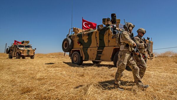 (FILES) In this file photo taken on September 08, 2019 US troops walk past a Turkish military vehicle during a joint patrol with Turkish troops in the Syrian village of al-Hashisha on the outskirts of Tal Abyad town along the border with Turkish troops - Sputnik International
