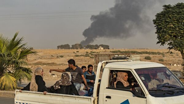Civilians ride a pickup truck as smoke billows following Turkish bombardment on Syria's northeastern town of Ras al-Ain in the Hasakeh province along the Turkish border on October 9, 2019 - Sputnik International
