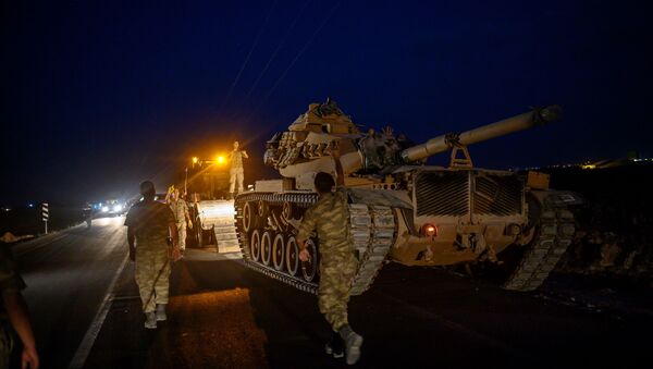 A Turkish army's tank drives down from a truck as Turkish armed forces drive towards the border with Syria near Akcakale in Sanliurfa province on October 8, 2019 - Sputnik International