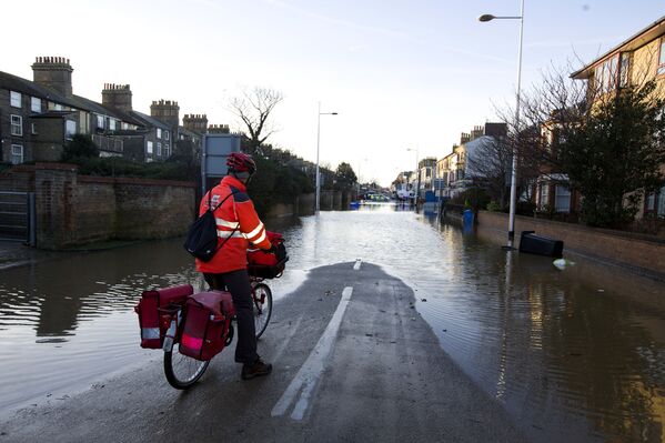 A postman stops and looks at a flooded street in Lowestoft, in the east of England, on December 6, 2013 after a tidal surge hit locations along the east coast of Britain.   - Sputnik International