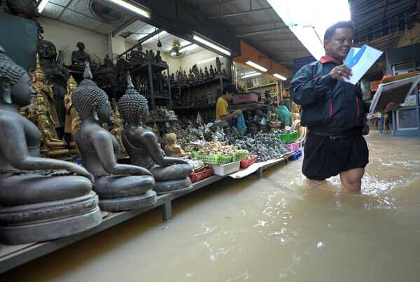 A Thai postman (R) walks through floodwaters at a market in Bangkok on October 27, 2010.  - Sputnik International