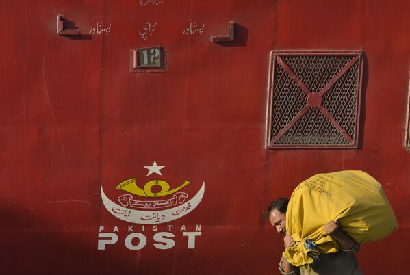 A Pakistani postal worker carries posts at a railway station in Lahore on October 8, 2017, ahead of the World Post Day. - Sputnik International
