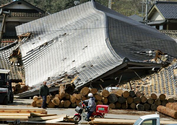 A helmeted postman on a motorcycle rumbles past flattened buildings at Wajima, one of the areas hit hardest in Ishikawa prefecture (state), northern Japan, on Monday March 26, 2007. - Sputnik International