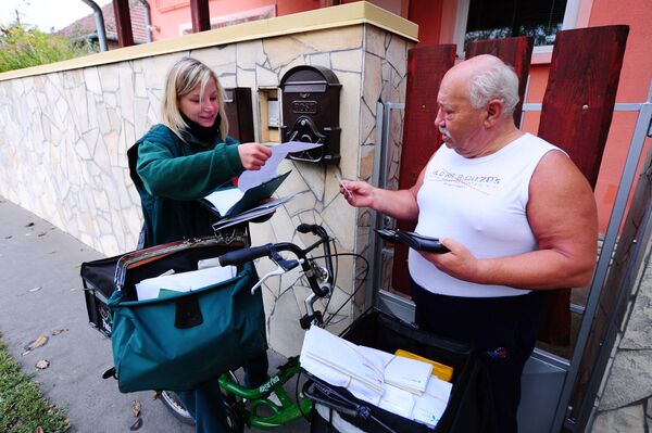 An official of the 'Magyar Posta' (Hungarian Post Company) Bernadett Kasza delivers a letter to a man in her district in Budapest on October 18, 2013.  - Sputnik International