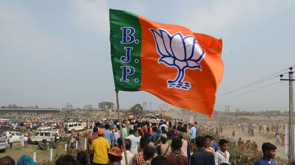 Indian supporters of the Bharatiya Janata Party (BJP) carry a party flag on their way to attend a campaign rally while wearing masks of Indian Prime Minister Narendra Modi ahead of the national elections in Siliguri, 3 April 2019 - Sputnik International