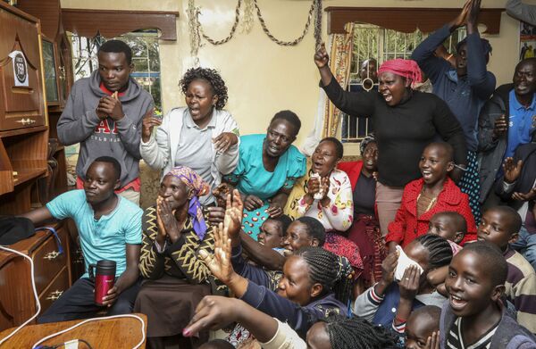 Eliud Kipchoge's mother Janet Rotich, seated 2nd left wearing a headscarf, watches on television and celebrates her son's sub-2 hour marathon time, with friends and neighbors, in Kapsisiywa village in the Rift Valley of Kenya Saturday, Oct. 12, 2019. Eliud Kipchoge sent shockwaves through the world of sport by becoming the first athlete to break the two-hour barrier for a marathon, at an event set up for the attempt in Austria, although it will not count as a world record.  - Sputnik International