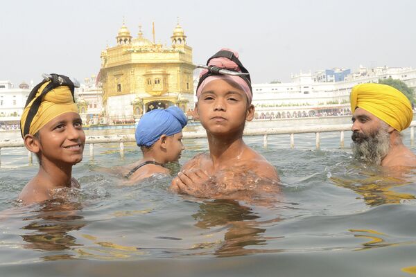 Sikh devotees take a dip in the holy sarovar (water tank), on the occasion of the birth anniversary of the fourth Sikh Guru Ram Das at the Golden Temple in Amritsar on October 15, 2019.  - Sputnik International