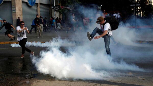 A demonstrator kicks a tear gas canister during a protest against the increase in the subway ticket prices in Santiago, Chile, October 18 - Sputnik International