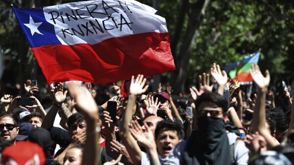 Protesters wave a Chilean flag, marked with a message that reads in Spanish: Pinera quit during a demonstration in Santiago, Chile, Monday, Oct. 21, 2019. - Sputnik International