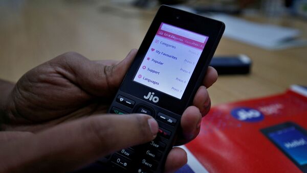 A sales person displays features of JioPhone as he poses for a photograph at a store of Reliance Industries' Jio telecoms unit, on the outskirts of Ahmedabad, India, September 26, 2017 - Sputnik International