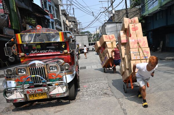 Workers pull carts loaded with goods next to a passenger jeepney along a street in Chinatown district of Manila on October 22, 2019.  - Sputnik International