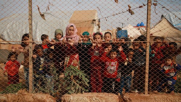 Displaced Syrian children stand behind a fence outside their tents in a camp set up near the village of Kafr Lusin, in Idlib's northern countryside near the Syria-Turkey border, on October 22, 2019. - Sputnik International