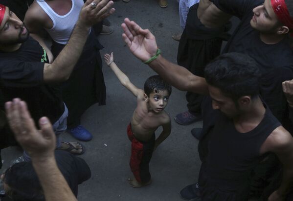 A Shiite Muslim child beats his chest next to his father during a procession to mark the end of the 40 day mourning period following the anniversary of the 7th century death of Imam Hussein, the Prophet Muhammad's grandson and one of Shiite Islam's most beloved saints, in Lahore, Pakistan, Sunday, Oct. 20, 2019.  - Sputnik International