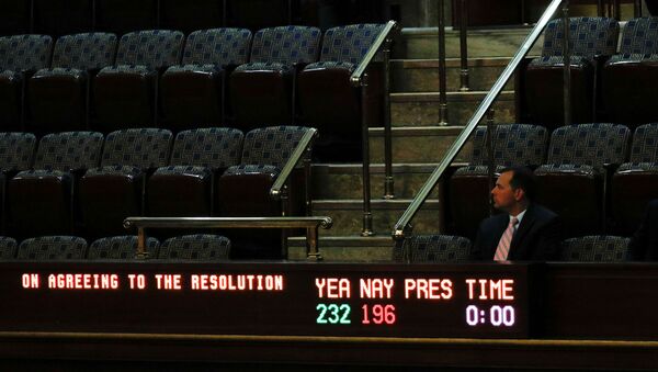 A man sits in the visitors gallery above the floor of the U.S. House of Representatives as a display board shows the final vote tallies of 232 Yea and 196 Nay on a resolution that outlines the next steps in the impeachment inquiry of U.S. President Donald Trump on Capitol Hill in Washington, U.S., October 31, 2019 - Sputnik International