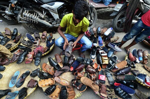 A Bangladeshi street shoe vendor arranges shoes as he prepares his display in Dhaka on October 30, 2019. - Sputnik International