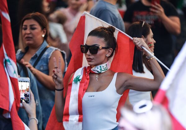 A Lebanese demonstrator waves a national flag at the Martyrs' Square in the centre of the capital Beirut on October 27, 2019, during ongoing anti-government protests. - Sputnik International