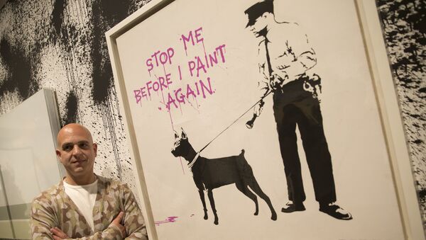 Curator Steve Lazarides poses for a portrait next to at art work by British artist Banksy, during a press preview of an unauthorized retrospective exhibition showing some 70 works of art in London, Friday, June, 6, 2014 - Sputnik International