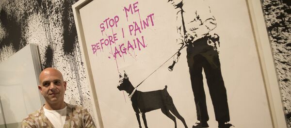 Curator Steve Lazarides poses for a portrait next to at art work by British artist Banksy, during a press preview of an unauthorized retrospective exhibition showing some 70 works of art in London, Friday, June, 6, 2014 - Sputnik International