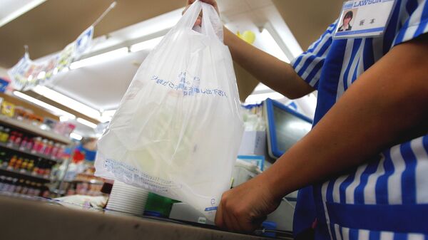A store clerk hands a plastic bag of goods at a pay counter at a convenience store in Tokyo Thursday, June 8, 2006. Facing criticism from environmentalists, Japan is now trying to cut back on plastic waste with a new law that gives the government the right to warn and give corrective orders to retailers that don't make enough efforts to save on plastic. - Sputnik International