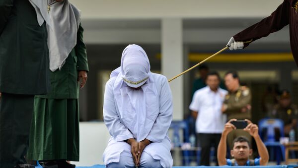 A woman is whipped in public by a member of the Sharia police in Banda Aceh on October 31, 2019, after being caught having an affair with Aceh Ulema Council (MPU) member Mukhlis.  - Sputnik International