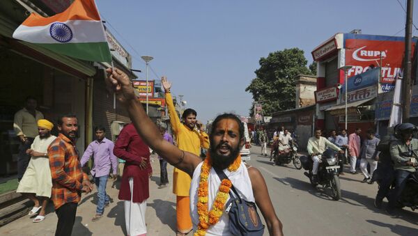 A Hindu devotee waves an Indian national flag and celebrates a verdict in a decades-old land title dispute between Muslims and Hindus, in Ayodhya, India , Saturday, Nov. 9, 2019.  - Sputnik International