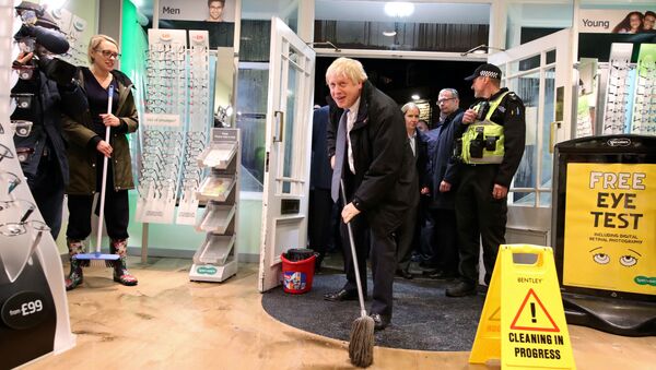 Britain's Prime Minister Boris Johnson mops the floor to help with the clean-up at an opticians during a visit to the flood-hit town of Matlock, Derbyshire, Britain November 8, 2019. Picture taken November 8, 2019. Danny Lawson - Sputnik International