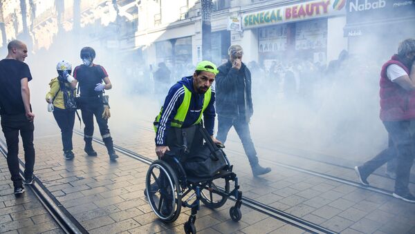 A man pushes his wheelchair away from teargas on Novemebr 9, 2019 in the center of Montpellier, southern France, during a demonstration as part of an nationwide anti-government protest called by the yellow vest movement (gilets jaunes). - Sputnik International
