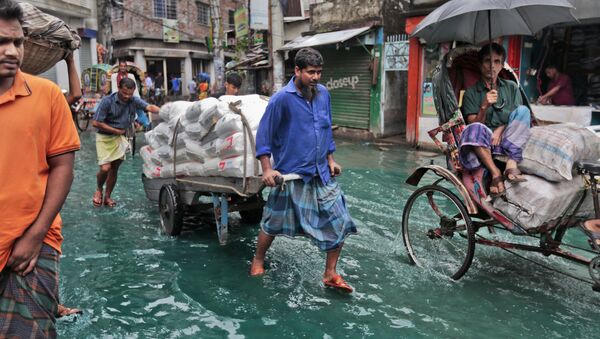 Bangladeshi men pull a loaded cart through a waterlogged street after heavy rainfall in Dhaka, Bangladesh, Saturday, May 21, 2016.  - Sputnik International