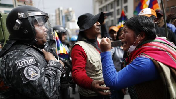 A supporter of Bolivia's former President Evo Morales yells at a police officer, telling him to respect the nation's indigenous people in La Paz, Bolivia, Tuesday, Nov. 12, 2019. Former President Evo Morales, who transformed Bolivia as its first indigenous president, flew to exile in Mexico on Tuesday after weeks of violent protests, leaving behind a confused power vacuum in the Andean nation. (AP Photo/Natacha Pisarenko) - Sputnik International