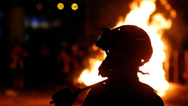 A protester is seen in front of a fire in the Mong Kok area in Hong Kong - Sputnik International