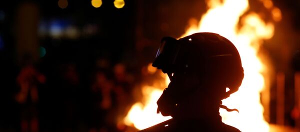 A protester is seen in front of a fire in the Mong Kok area in Hong Kong - Sputnik International