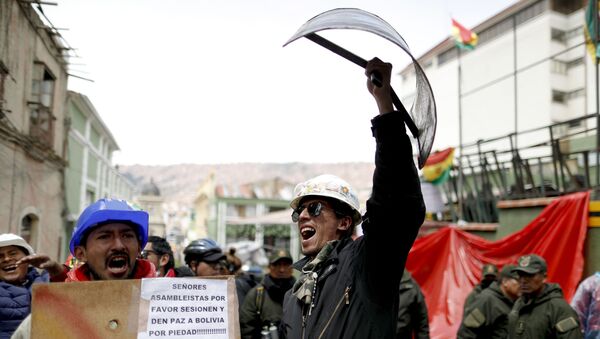 Opponents of former Bolivian President Evo Morales hold shields at a barricade set up by protesters outside presidential palace in La Paz, Bolivia, Monday, Nov. 11, 2019. - Sputnik International