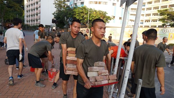 Personnel from the Chinese People's Liberation Army barracks in Hong Kong emerged on to the city streets on November 16, 2019, to help the clean-up after a week of violence and disruption caused by pro-democracy protesters. - In a rare and highly symbolic movement by a garrison which is confined to the barracks under Hong Kong's mini-constitution, scores of men with crewcuts and identical gym kits conducted a lightning-quick removal of bricks and debris near their base. - Sputnik International