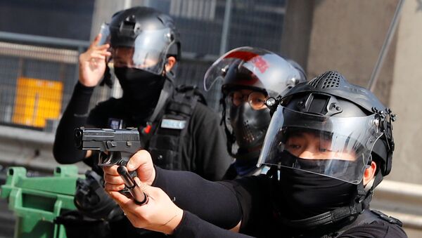 Riot police officer points a gun at protesters attempting to escape the campus of Hong Kong Polytechnic University (PolyU) during clashes with police in Hong Kong - Sputnik International