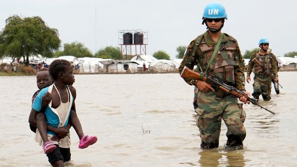 A girl holding a child walks past UN peacekeepers, after heavy rains and floods forced hundreds of thousands of people to leave their homes, in the town of Pibor, Boma state, South Sudan, November 6, 2019. - Sputnik International