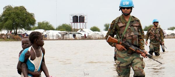 A girl holding a child walks past UN peacekeepers, after heavy rains and floods forced hundreds of thousands of people to leave their homes, in the town of Pibor, Boma state, South Sudan, November 6, 2019. - Sputnik International