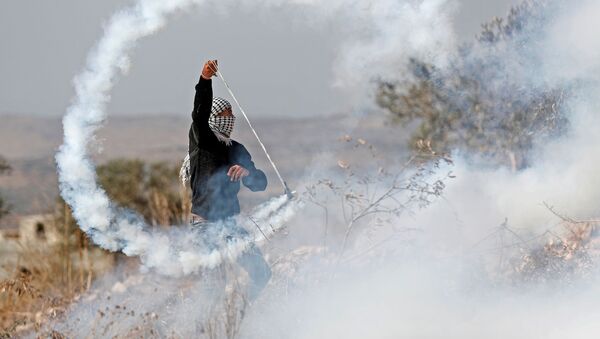 A Palestinian demonstrator returns a tear gas canister during a protest against Jewish settlements in Kofr Qadom, in the Israeli-occupied West Bank November 22, 2019 - Sputnik International