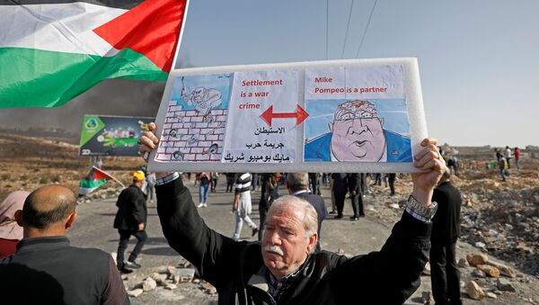 A demonstrator holds a sign during a protest as Palestinians call for a day of rage over U.S. decision on Jewish settlements, near the Jewish settlement of Beit El in the Israeli-occupied West Bank November 26, 2019. - Sputnik International